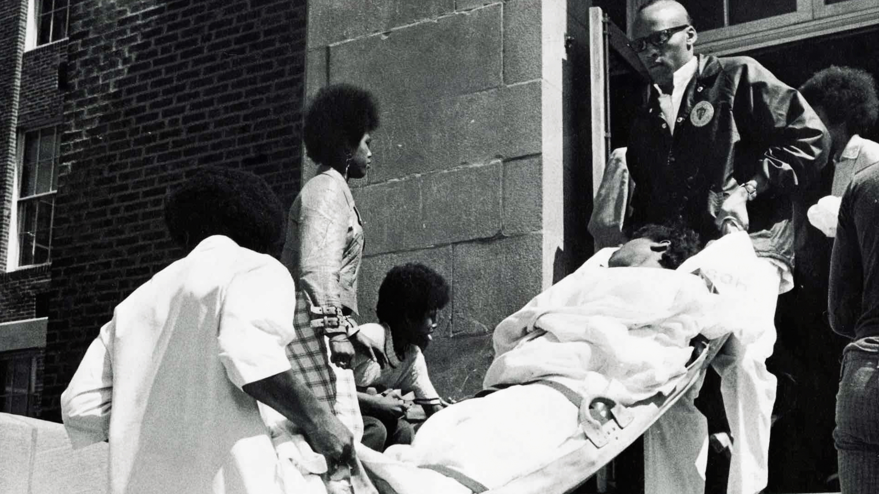Freedom House Ambulance EMTs James Kyte & Mitchell Brown carrying unconscious female student from Pittsburgh Schenley High School. 1971-1972 (source: John Moon)
